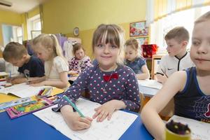 Children in a drawing lesson in kindergarten. Preschooler girl with pencil and notebook photo