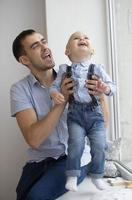 Happy father plays with the baby. A man with a small son near the window photo