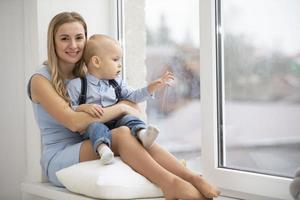 Mom with her son at home near the window. photo