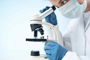 laboratory assistant wearing a medical mask looking through a microscope Professional research experiment photo