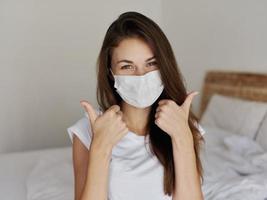 cheerful woman in medical mask showing thumbs up photo