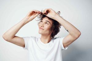 alegre chico con despeinado pelo en un blanco camiseta emociones de cerca foto