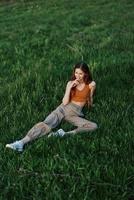 A woman lies on fresh spring green grass in a park without mosquitoes or ticks and enjoys relaxing while watching the sunset. The concept of safe outdoor recreation photo