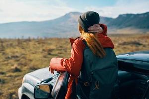 traveler in a hat with a backpack near the car door in nature photo