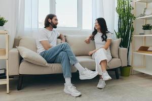 masculino y hembra asiático amigos sentado en el sofá y teniendo divertido hablando a cada otro con un sonrisa teniendo un bueno hora juntos. estilo de vida en felicidad a hogar foto