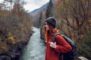mujer caminante en el otoño bosque en el puente cerca el río viaje foto
