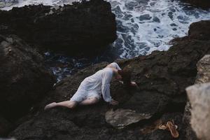 woman lying on her back on a rocky seashore nature photo