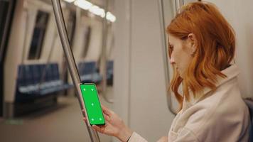 Side view female watching at green screen phone in subway train. video