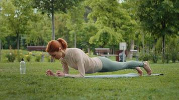 Woman is planking outdoor during fitness session. video