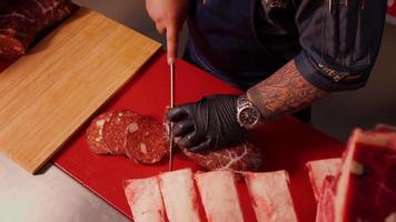 parte superior ver Carnicero rebanar hecho a mano salchicha en un carnicería cocina. video