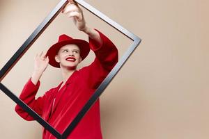 fashionable woman with wooden frame posing red suit beige background photo