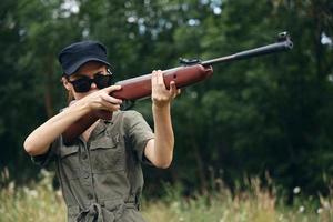 Woman soldier Sunglasses weapon aiming hunting green leaves photo