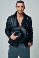 man in black leather jacket hat posing fashion confident light background photo