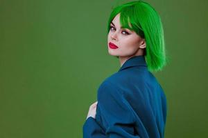 Beauty Fashion woman wearing a green wig blue jacket posing green background unaltered photo