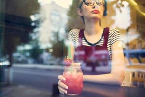 mujer con corto pelo se sienta a un mesa en un café cóctel vacaciones foto