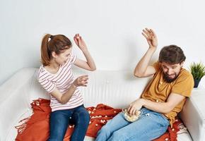 cheerful man and woman on the couch with popcorn and red plaid flower in a pot emotions photo