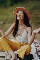 A hippie woman meditating in nature in the lotus position in the sunset light photo