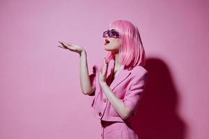 retrato de un encantador dama gestos con su manos con un rosado chaqueta inalterado foto