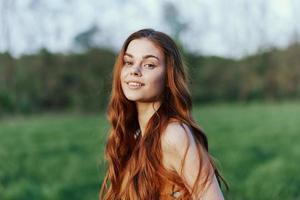 A woman smiles and is happy in nature in a green park, looks at the sunset and smiles. Healthy lifestyle concept photo