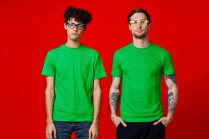 two friends are standing side by side in green T-shirts with glasses photo