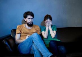 A married couple on the couch watching TV and popcorn indoors photo