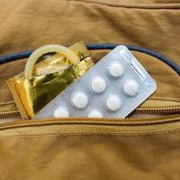 birth control pill and condom peeking out from pocket handbags photo