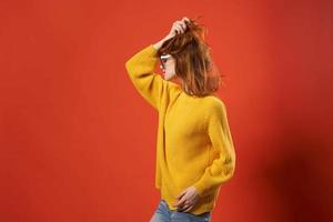 pretty woman in yellow sweater fashion glasses red background photo