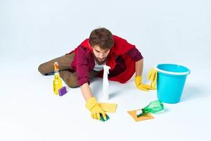 limpiador con limpieza suministros en un rojo impermeable en el piso de el casa interior foto