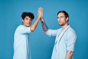 young guys in matching t-shirts and shirts fun greetings blue background friends photo