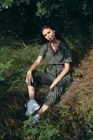 nice woman sits on the grass in the forest in overalls and sneakers photo