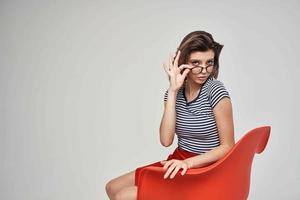 woman in a striped T-shirt sitting on the red chair modern style hairstyle photo