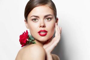 Woman with flower red lips hand near face naked shoulders makeup photo