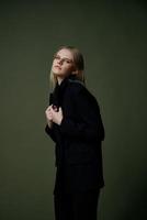 A concept for marketplaces and clothing brands. Full-length portrait of a blonde holding a jacket collar posing on a green background in the studio photo