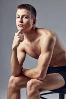 pensive sporty man with a pumped-up body sit on a chair close-up photo
