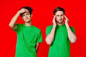 two men holding their heads in green T-shirts on a red background photo