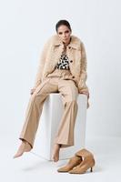 attractive fashionable woman wearing beige clothes barefoot posing sitting photo