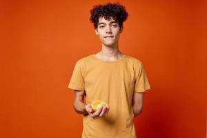 guy with curly hair oranges in hands fruit red background photo