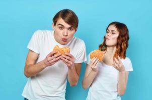 man and woman in t-shirts with hamburgers in the hands of fast food diet photo