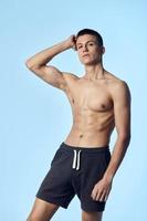 sporty man holding hand on head posing naked torso black shorts photo