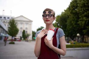 woman with short hair on the street in sunglasses with a drink photo