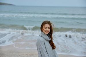 pretty woman in a sweater flying hair by the ocean tourism unaltered photo