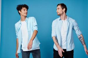 two friends in an unbuttoned shirt and in white t-shirts on a blue background gesturing with hands cropped view party photo