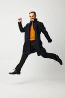 a man in stylish clothes, trousers and boots jumped up on a light background photo
