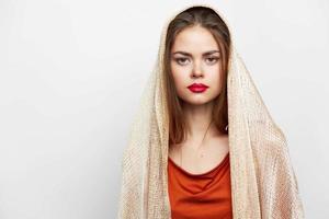 mujer con un bufanda glamour rojo labios Mira adelante modelo con productos cosméticos en el cara foto