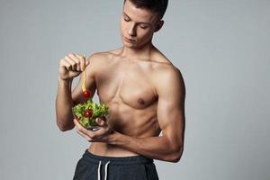 chico con un muscular torso y un ensalada bocadillo sano comida vitaminas foto