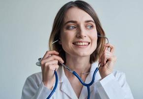 Professional doctor woman stands near the window and a stethoscope around her neck photo