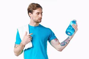 sports guy in blue t-shirt with a bottle of water in the river and tattoo white background fitness model photo