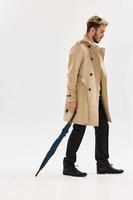 a man with a fashionable hairstyle umbrella in his hands coat rain protection men's fashion photo