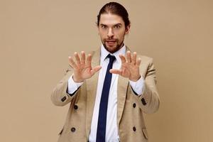 hermoso hombre en un traje con un Corbata posando beige antecedentes foto