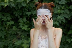 Portrait of a girl covered her eyes with her hands cosmetic mask skin care leaves in the background photo